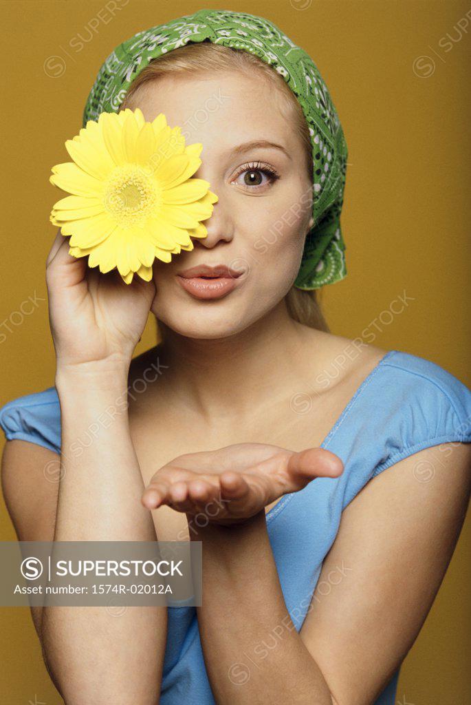 Stock Photo: 1574R-02012A Portrait of a young woman holding a flower in front of her eye