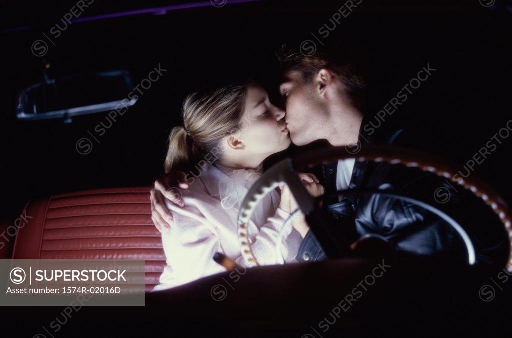 Stock Photo: 1574R-02016D Young couple kissing in a car