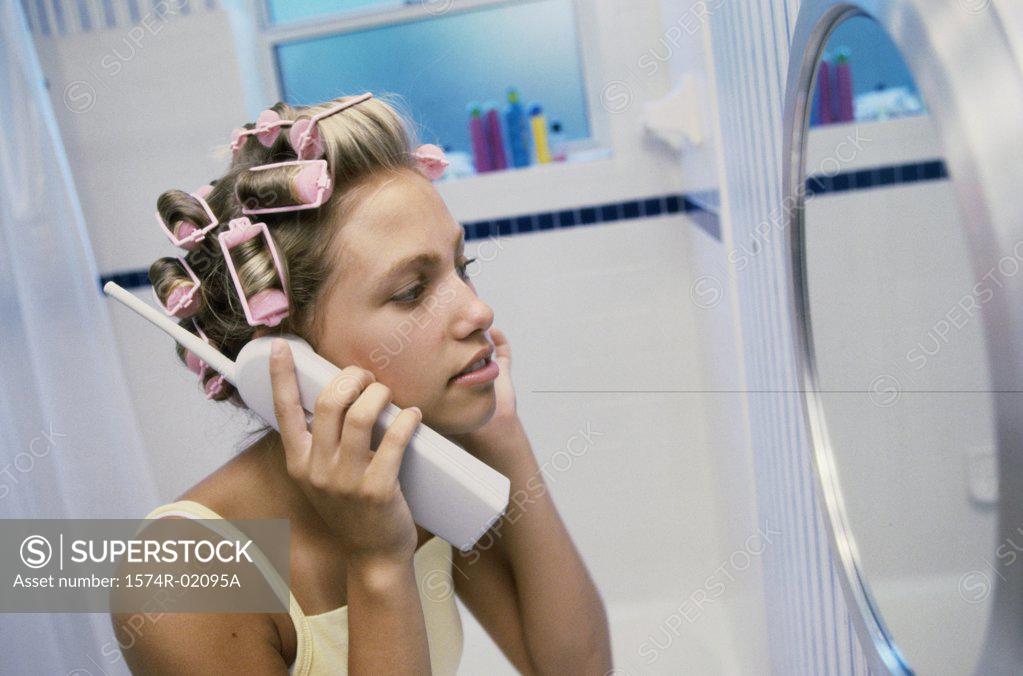 Stock Photo: 1574R-02095A Young woman with curlers in her hair talking on a telephone