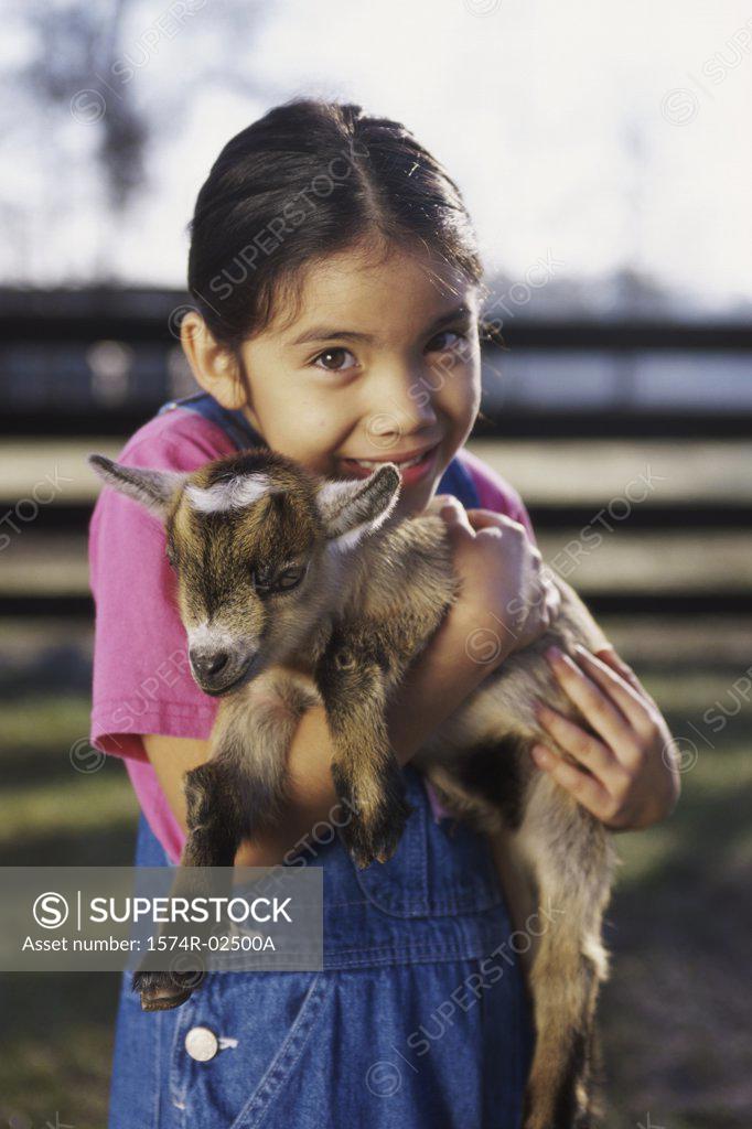 Stock Photo: 1574R-02500A Portrait of a girl holding a kid goat in her arms