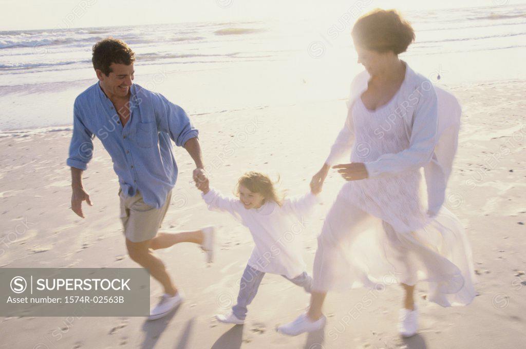 Stock Photo: 1574R-02563B Parents running on the beach with their daughter