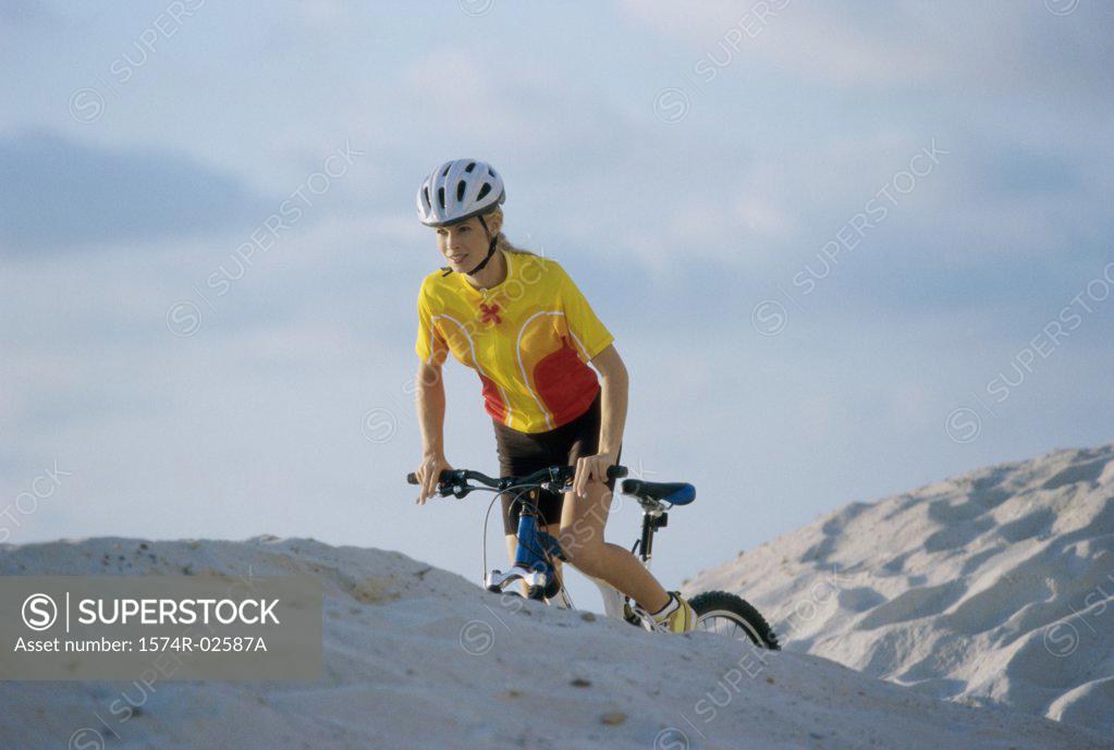 Stock Photo: 1574R-02587A Young woman cycling on sand