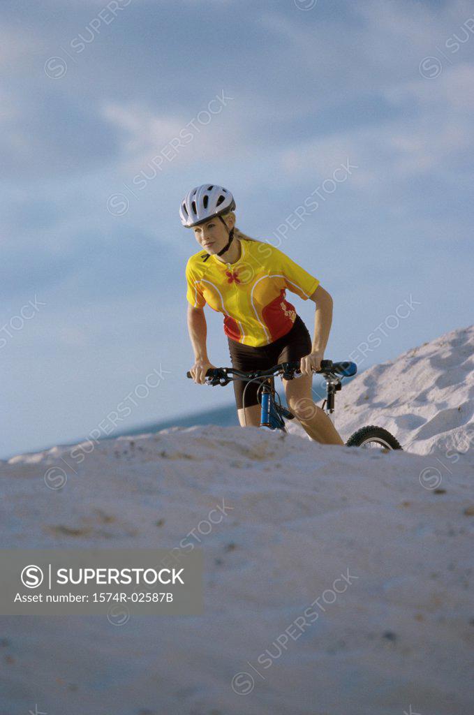 Stock Photo: 1574R-02587B Young woman cycling on sand