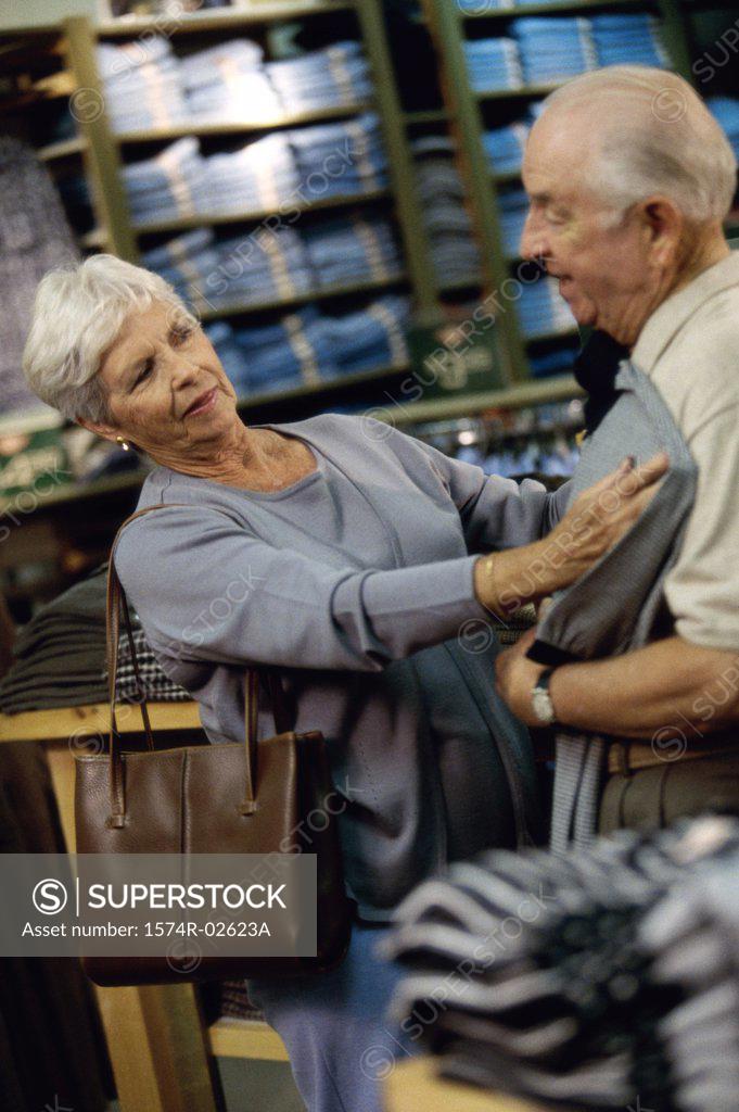 Stock Photo: 1574R-02623A Senior woman holding a t-shirt against a senior man in a clothing store