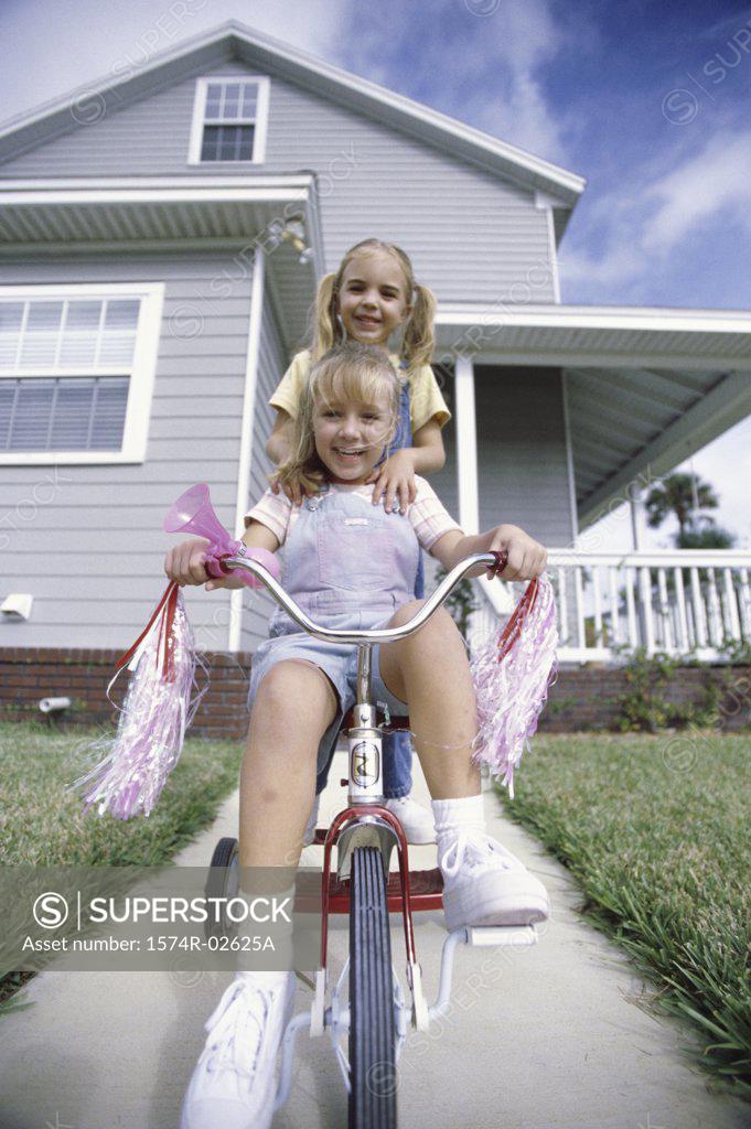 Stock Photo: 1574R-02625A Portrait of two girls riding a tricycle