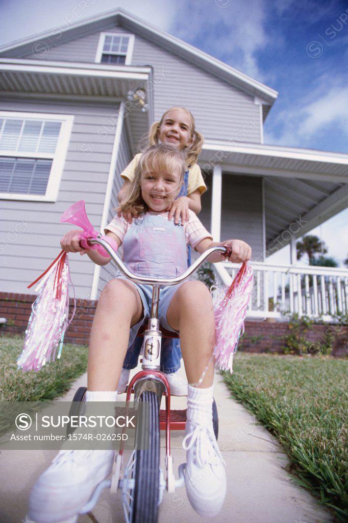 Stock Photo: 1574R-02625D Portrait of two girls riding a tricycle