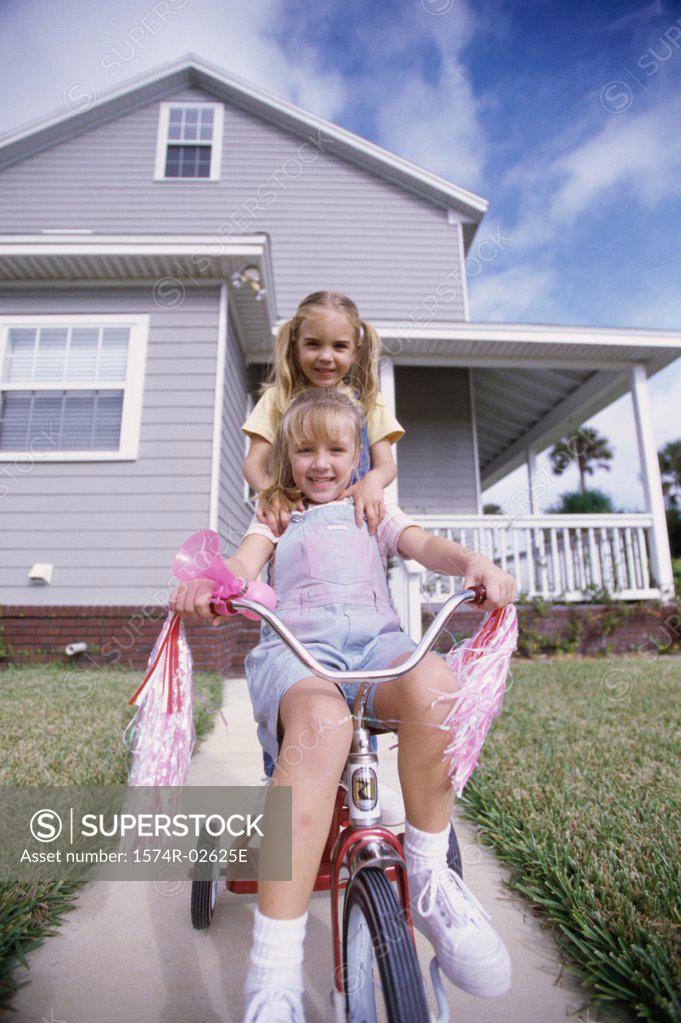 Stock Photo: 1574R-02625E Portrait of two girls riding a tricycle