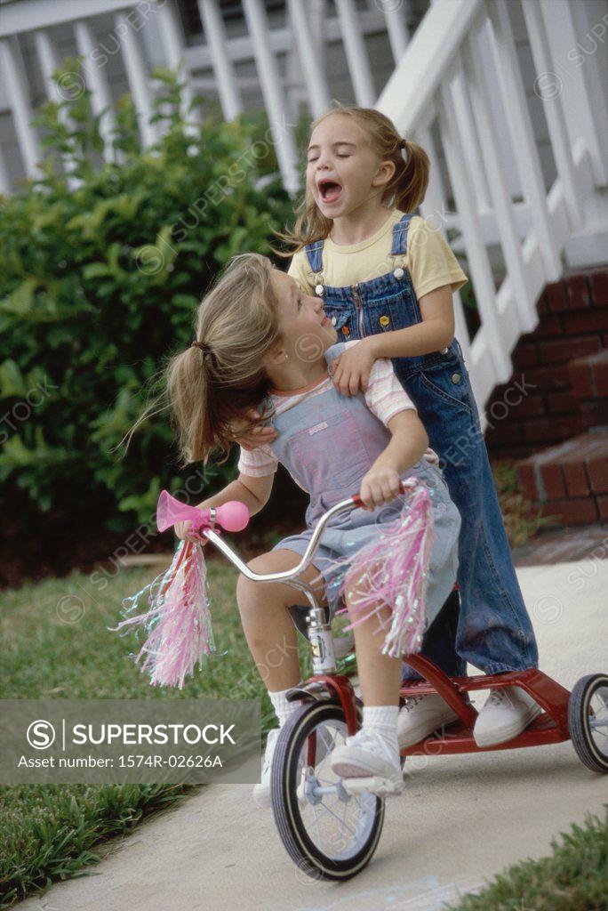 Stock Photo: 1574R-02626A Two girls playing on a tricycle