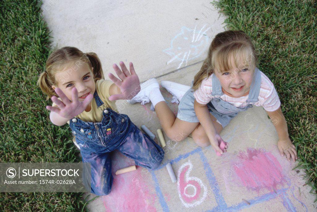 Stock Photo: 1574R-02628A Portrait of two girls drawing on the ground with chalk