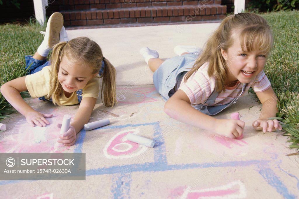 Stock Photo: 1574R-02630A Portrait of two girls drawing on the ground with chalk