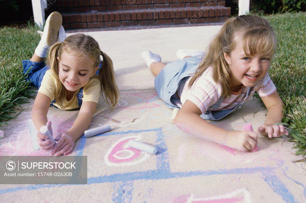 Stock Photo: 1574R-02630B Portrait of two girls drawing on the ground with chalk