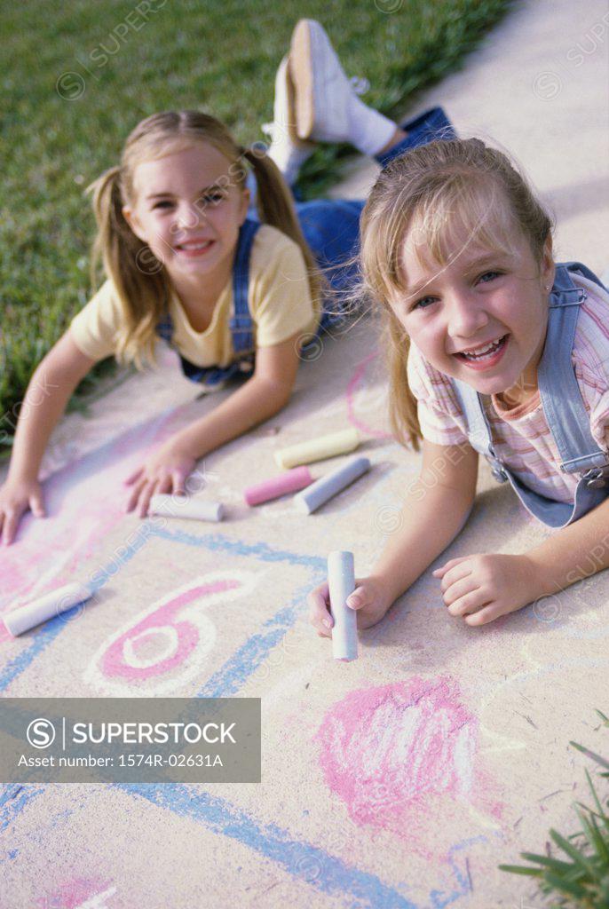 Stock Photo: 1574R-02631A Portrait of two girls drawing on the ground with chalk