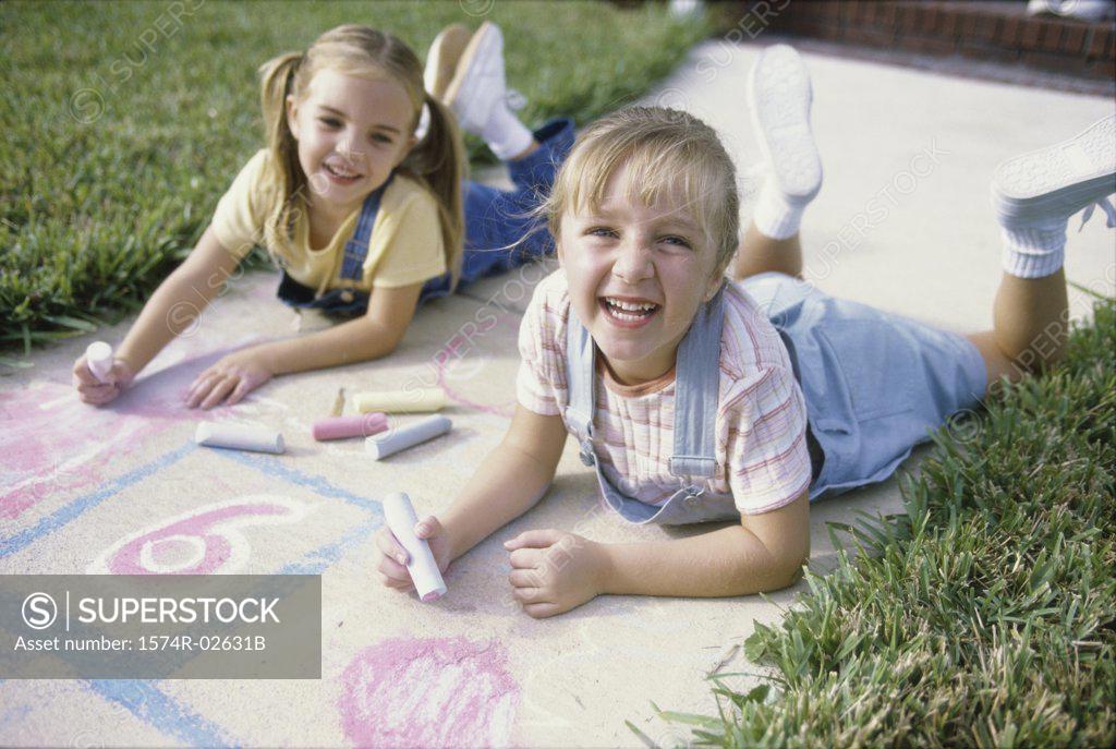 Stock Photo: 1574R-02631B Portrait of two girls drawing on the ground with chalk
