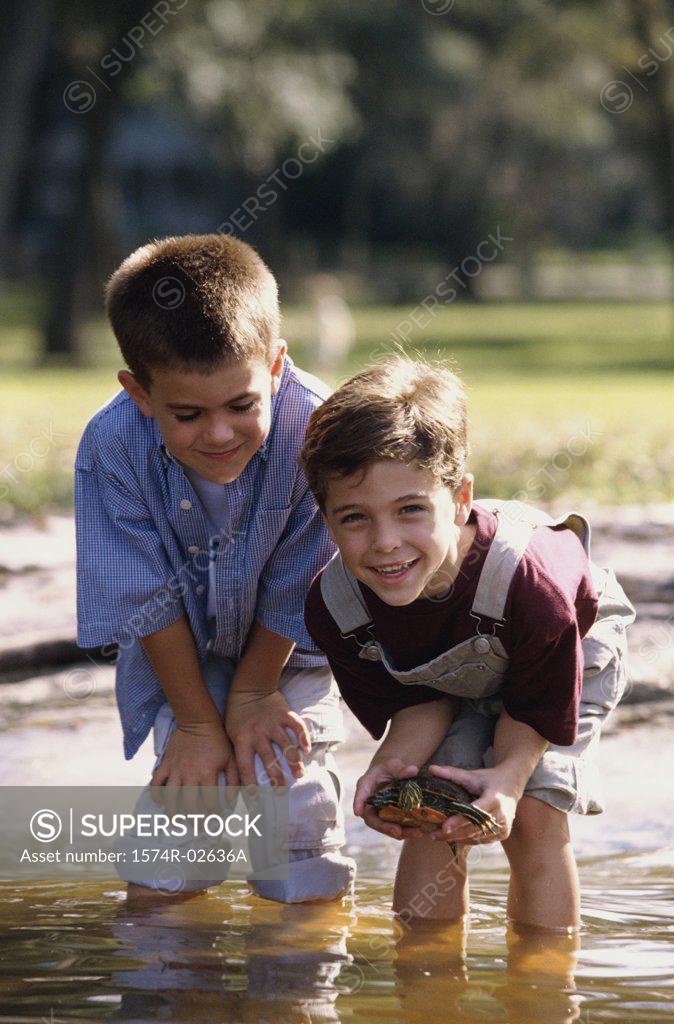 Stock Photo: 1574R-02636A Portrait of two boys standing in water holding a turtle