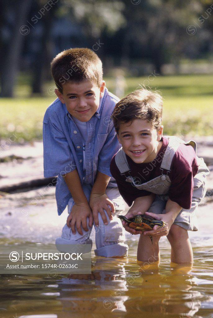 Stock Photo: 1574R-02636C Portrait of two boys standing in water holding a turtle