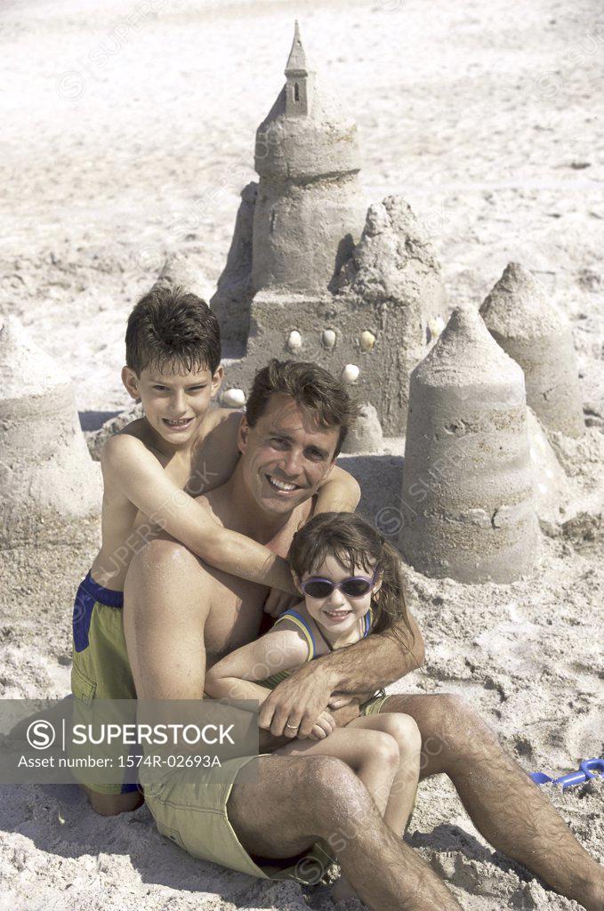 Stock Photo: 1574R-02693A Portrait of a father with his son and daughter sitting on the beach