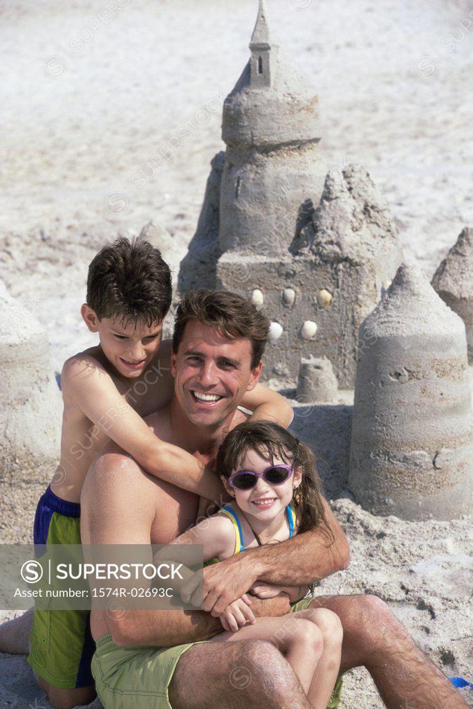 Stock Photo: 1574R-02693C Portrait of a father with his son and daughter sitting on the beach