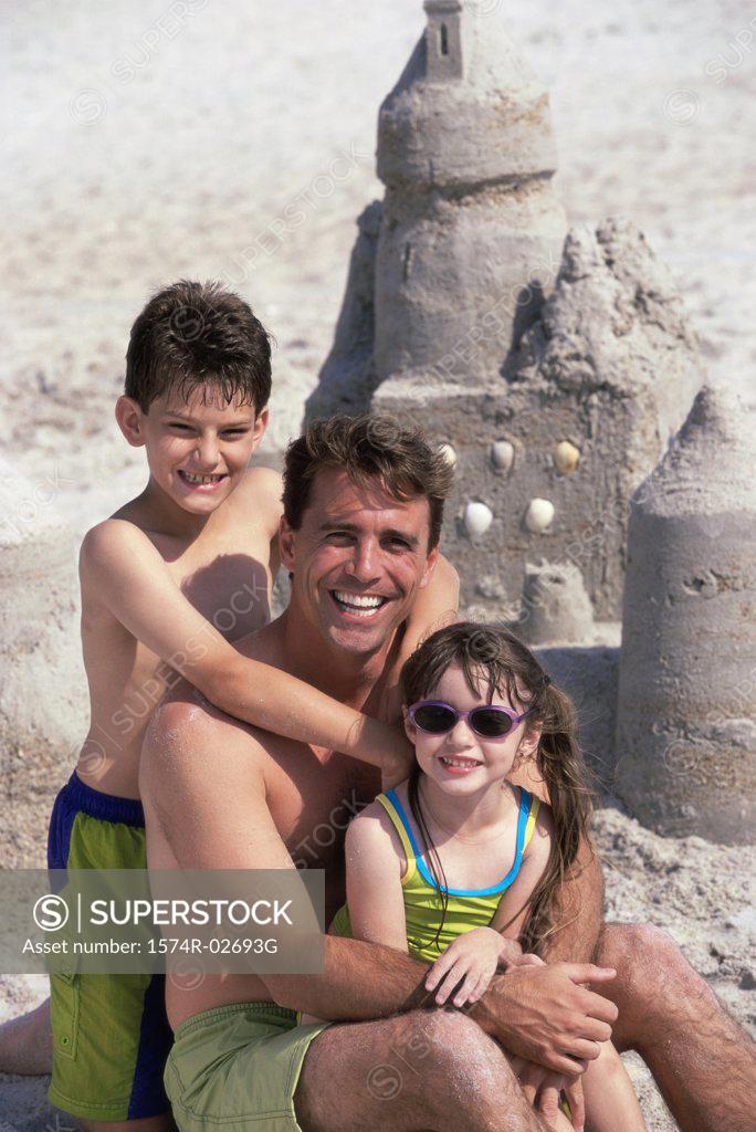 Stock Photo: 1574R-02693G Portrait of a father with his son and daughter sitting on the beach
