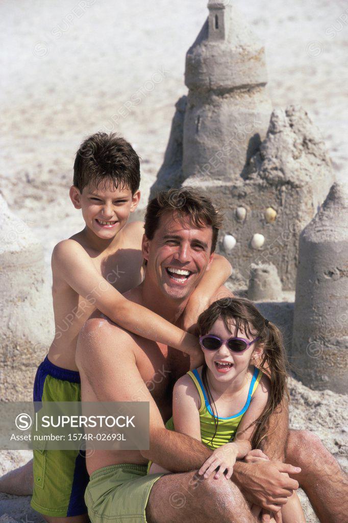 Stock Photo: 1574R-02693L Portrait of a father with his son and daughter sitting on the beach
