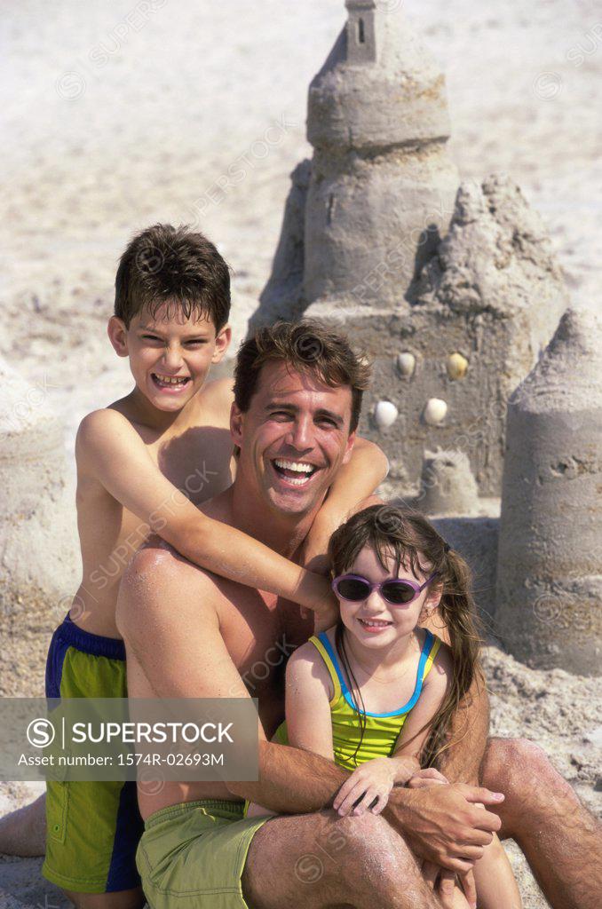 Stock Photo: 1574R-02693M Portrait of a father with his son and daughter sitting on the beach