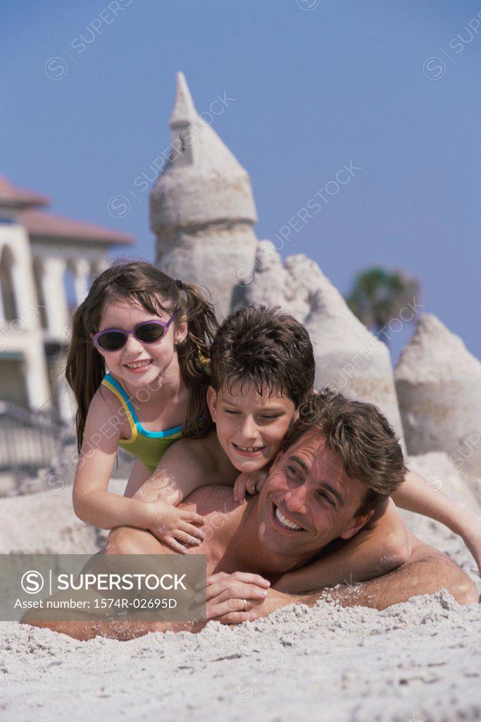 Stock Photo: 1574R-02695D Portrait of a father lying on the beach with his son and daughter
