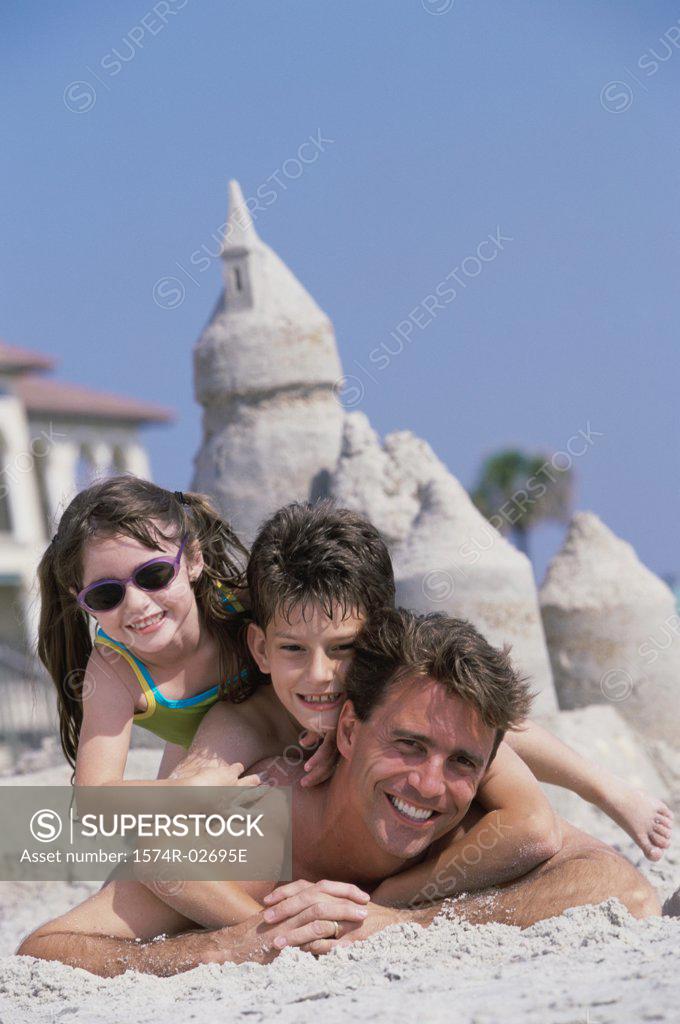 Stock Photo: 1574R-02695E Portrait of a father lying on the beach with his son and daughter