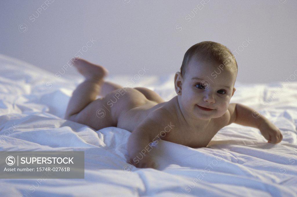 Stock Photo: 1574R-02761B Baby girl lying on a bed and smiling