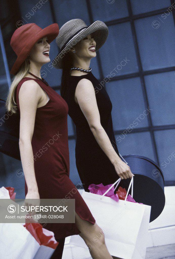 Stock Photo: 1574R-02804B Side profile of two young women walking with shopping bags
