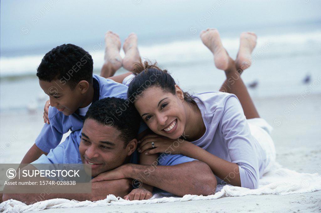 Stock Photo: 1574R-02883B Parents lying with their son on the beach