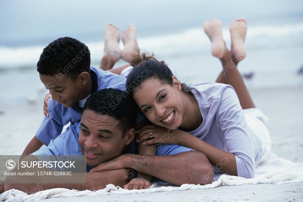 Stock Photo: 1574R-02883C Parents lying with their son on the beach