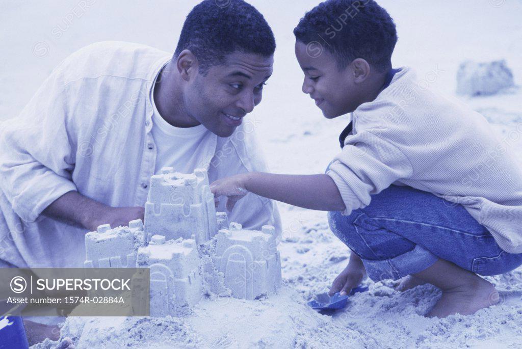 Stock Photo: 1574R-02884A Father and his son making sand castles on the beach