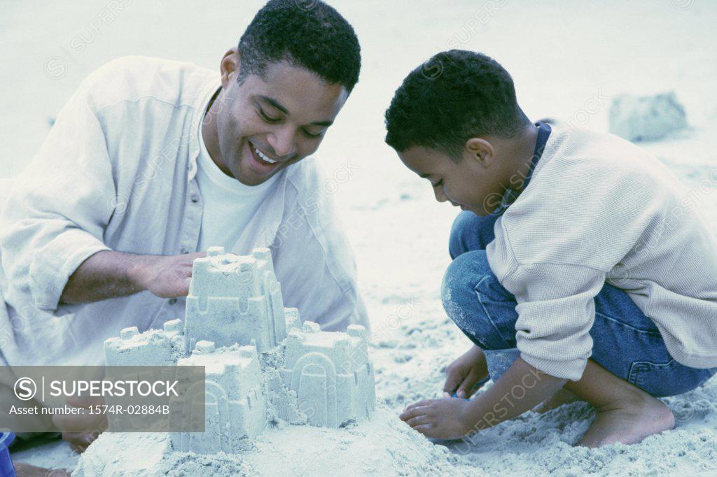 Stock Photo: 1574R-02884B Father and his son making sand castles on the beach