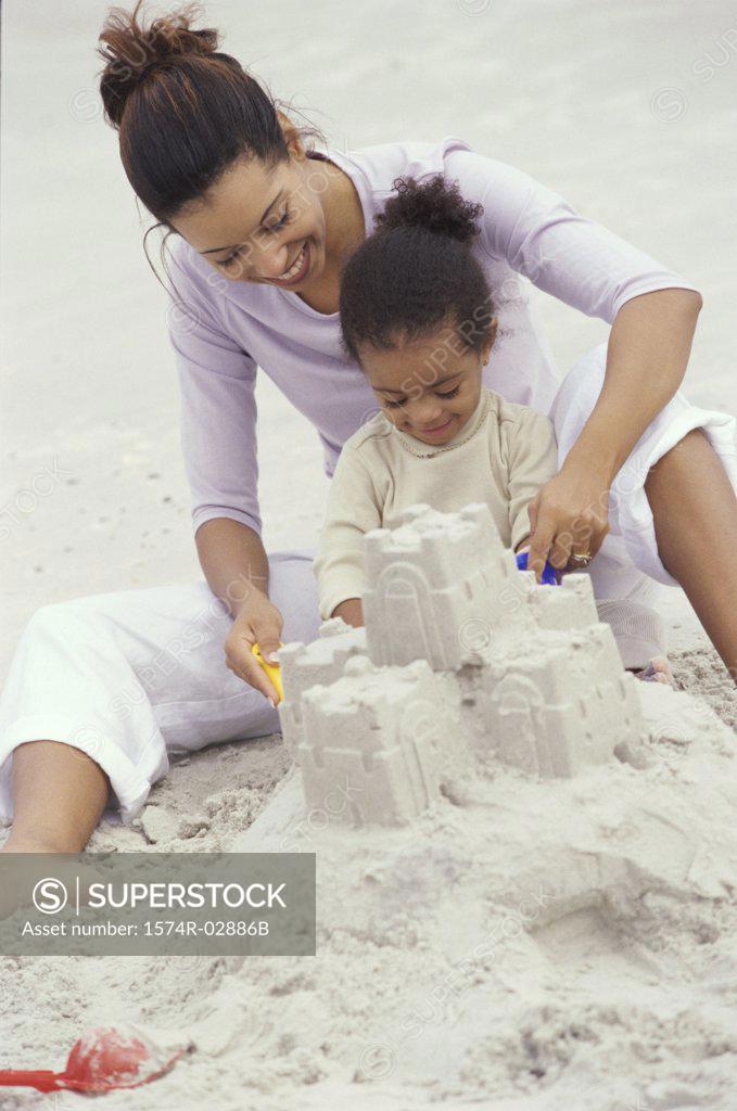 Stock Photo: 1574R-02886B Mother and her daughter making a sand castle on the beach