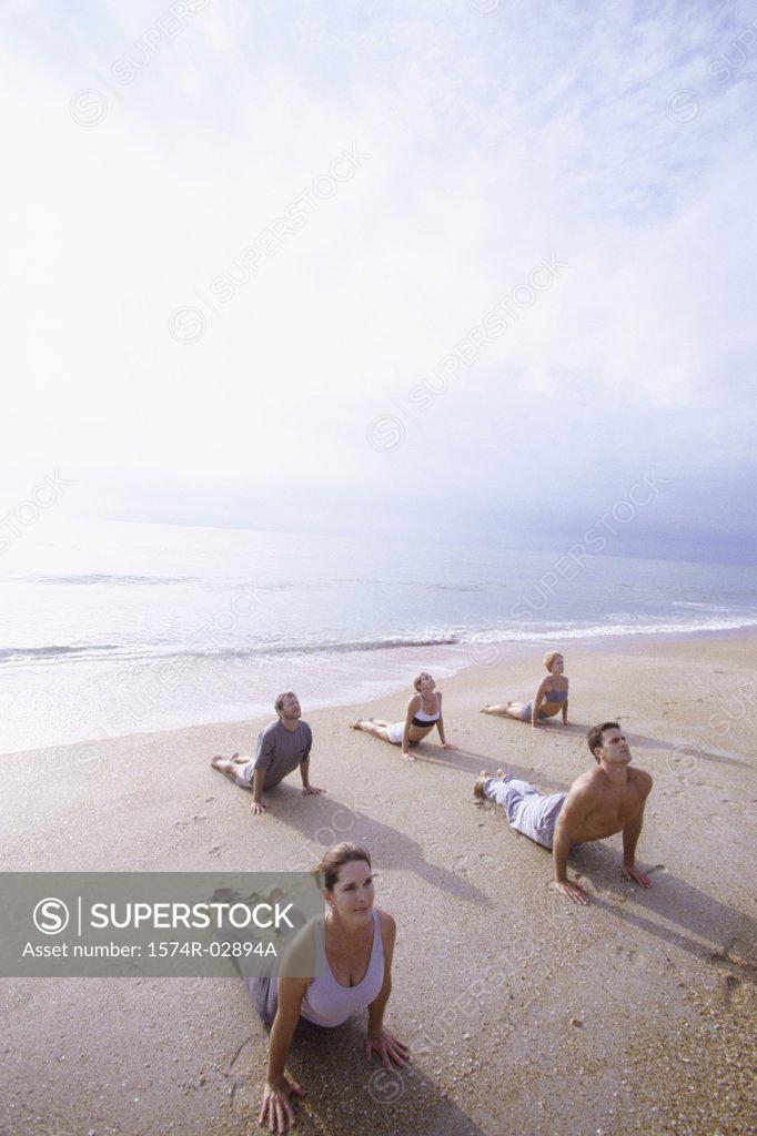 Stock Photo: 1574R-02894A Group of people performing yoga on the beach