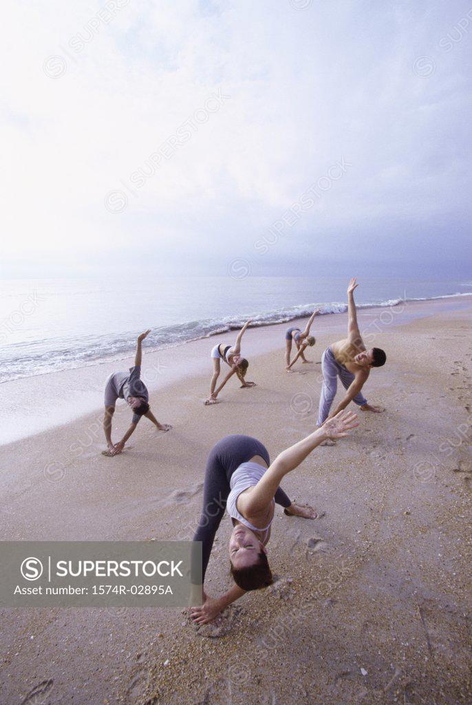 Stock Photo: 1574R-02895A Group of people performing yoga on the beach