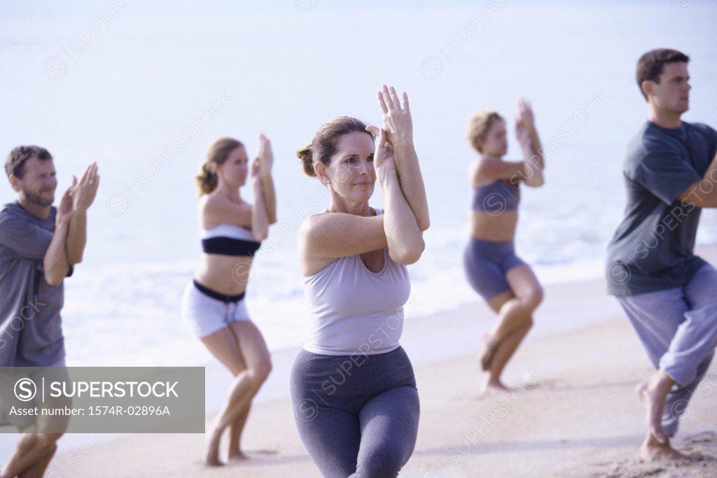 Stock Photo: 1574R-02896A Group of people performing yoga on the beach