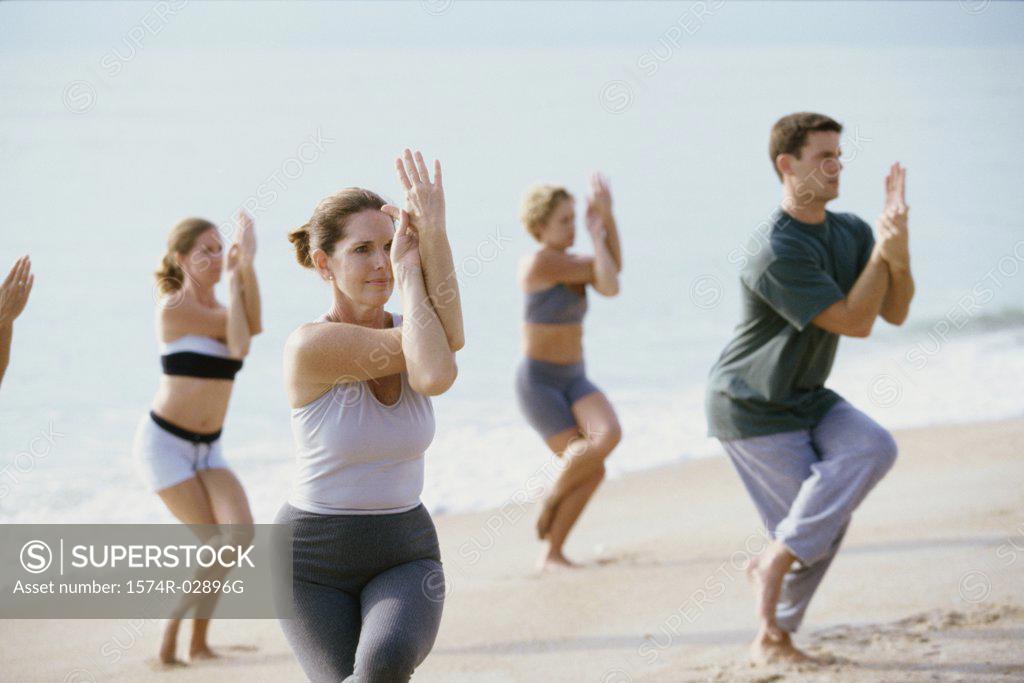 Stock Photo: 1574R-02896G Group of people performing yoga on the beach