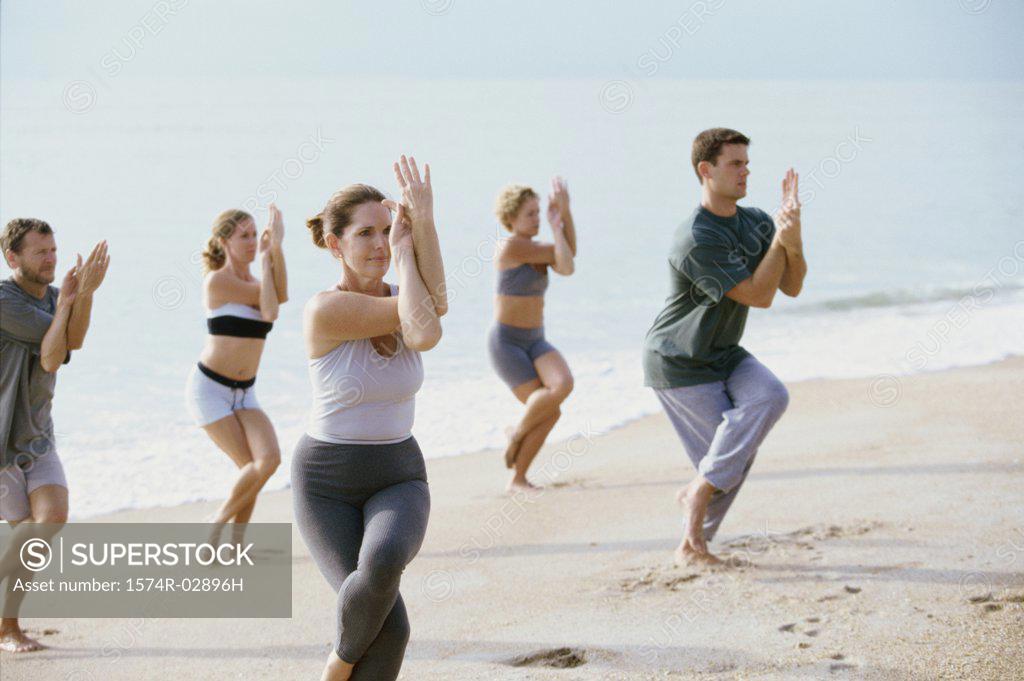 Stock Photo: 1574R-02896H Group of people performing yoga on the beach