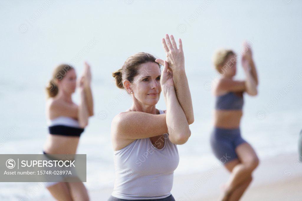 Stock Photo: 1574R-02897A Group of people performing yoga on the beach