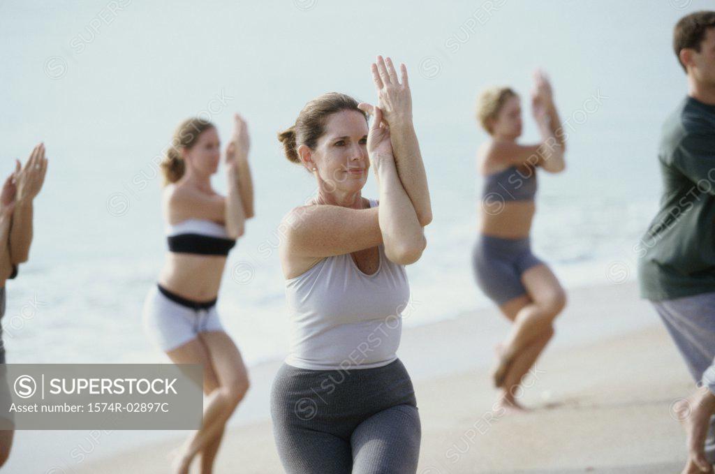 Stock Photo: 1574R-02897C Group of people performing yoga on the beach