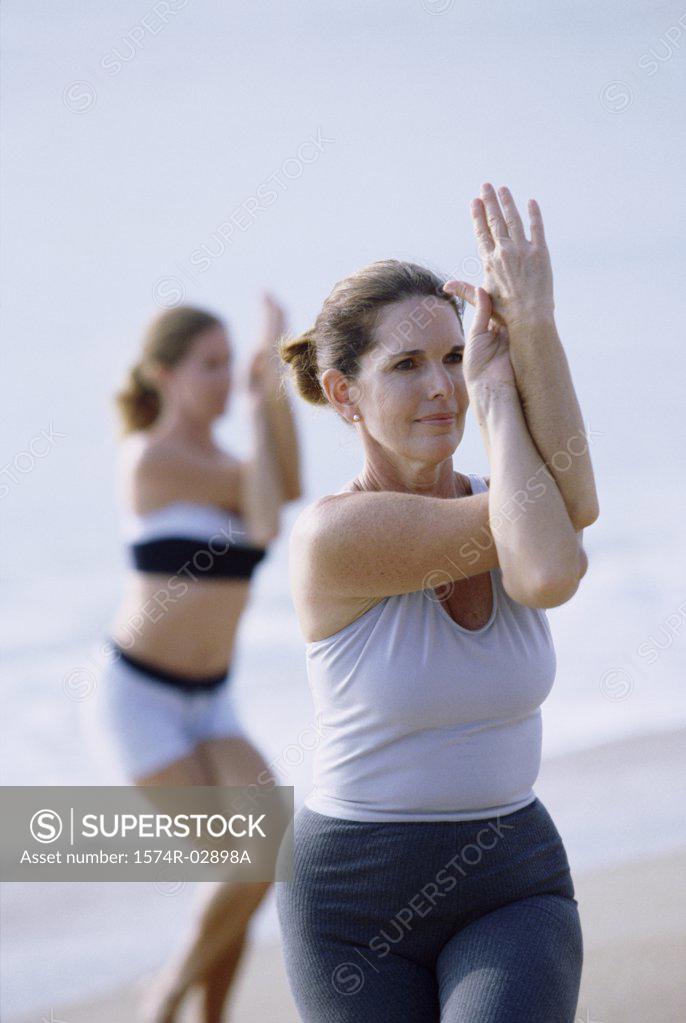Stock Photo: 1574R-02898A Two mid adult women performing yoga on the beach