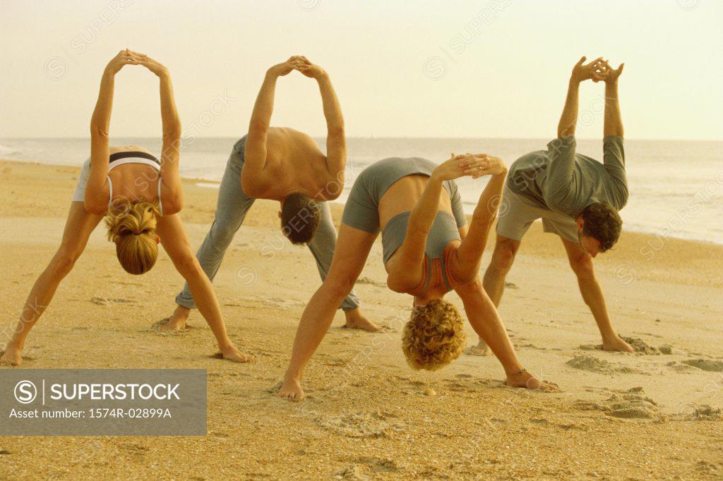 Stock Photo: 1574R-02899A Group of people performing yoga on the beach