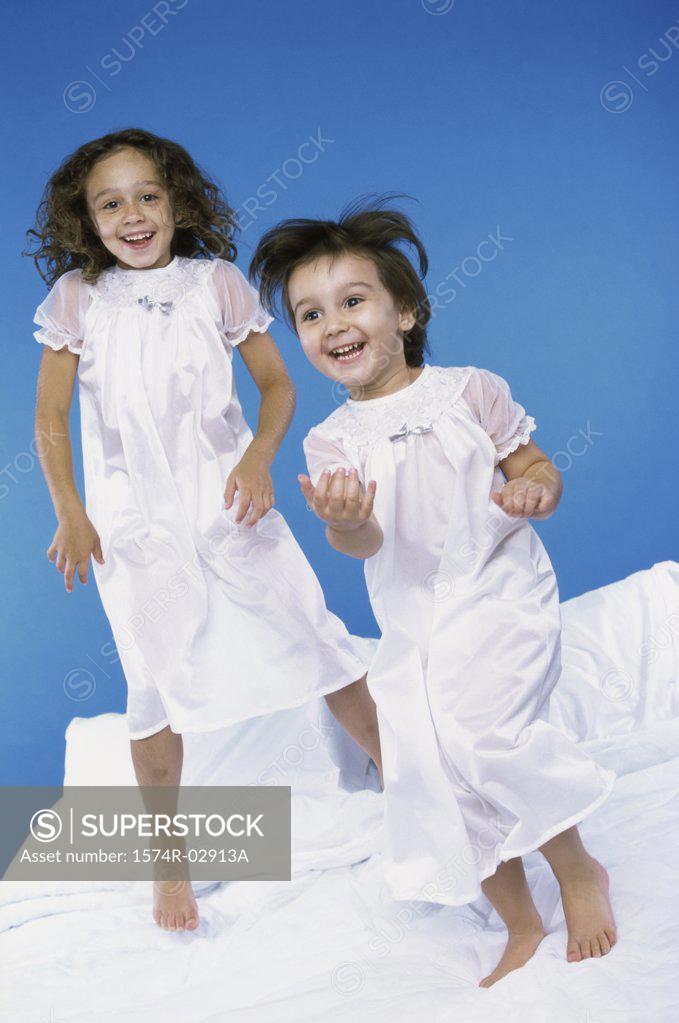 Stock Photo: 1574R-02913A Portrait of two girls jumping on a bed