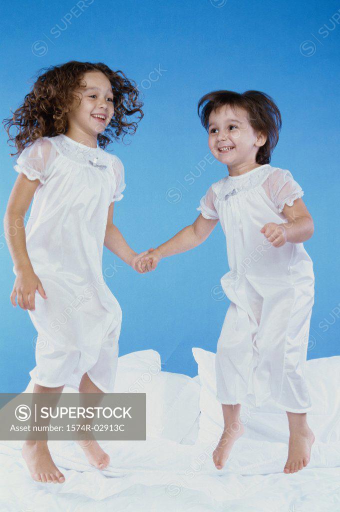 Stock Photo: 1574R-02913C Two girls jumping on a bed