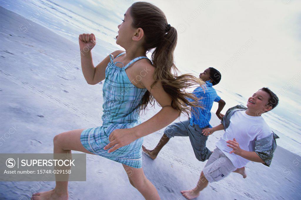Stock Photo: 1574R-02915B Two boys and a girl running together on the beach