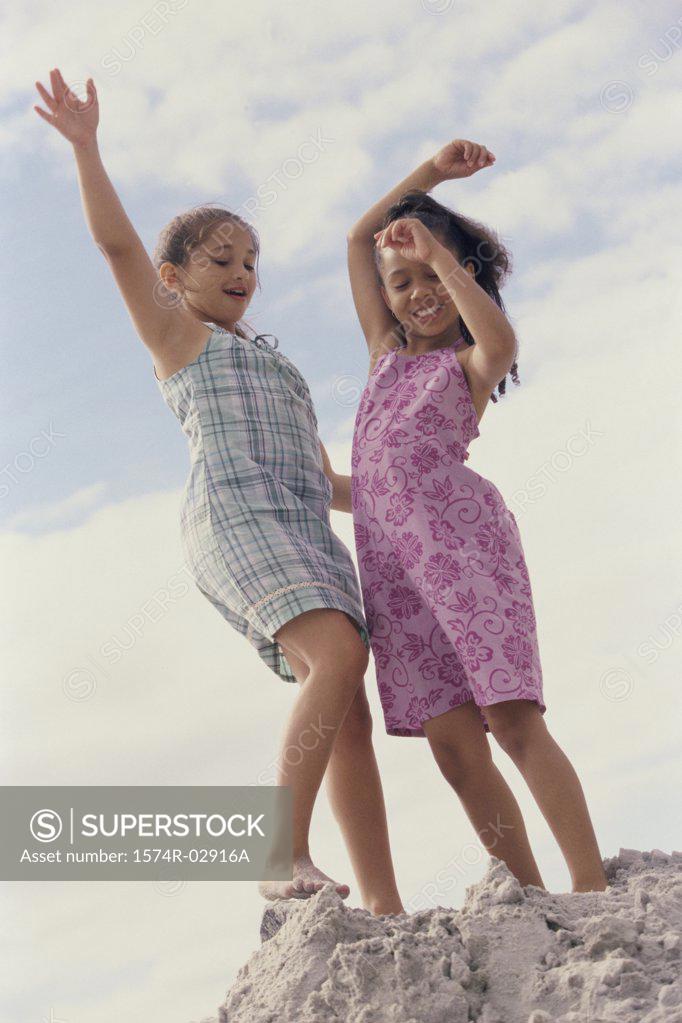 Stock Photo: 1574R-02916A Two girls standing on the beach with their arms raised