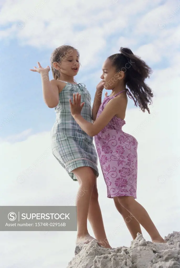 Low angle view of two girls standing on the beach