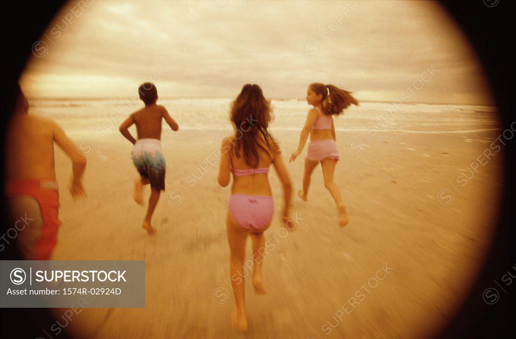 Stock Photo: 1574R-02924D Rear view of a group of children running on the beach