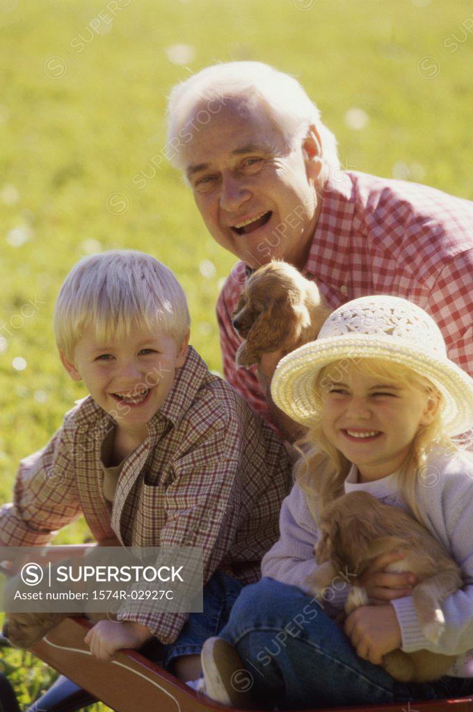 Stock Photo: 1574R-02927C Portrait of a grandfather with his grandson and granddaughter holding puppies