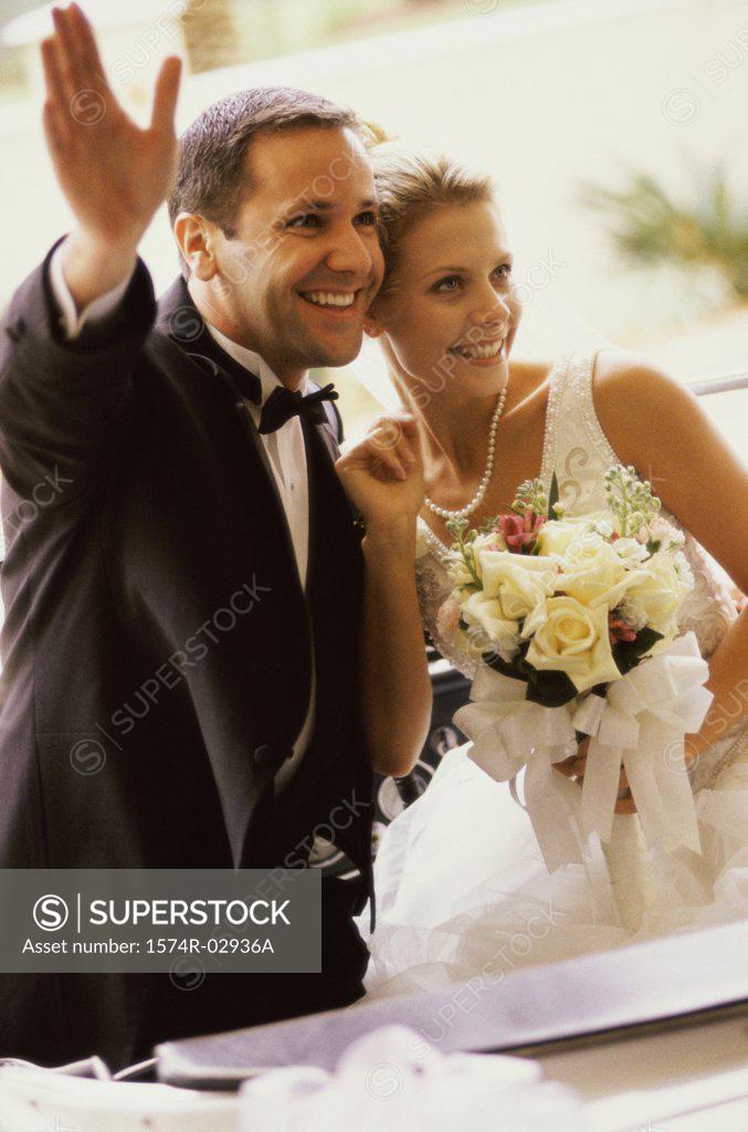 Stock Photo: 1574R-02936A Newlywed couple waving from a convertible car